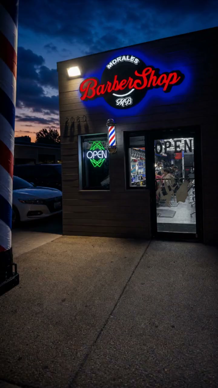 Interior de Morales Barbershop MB en Hyattsville: las estaciones de barbero con sillas rojas bajo el techo de panal iluminado