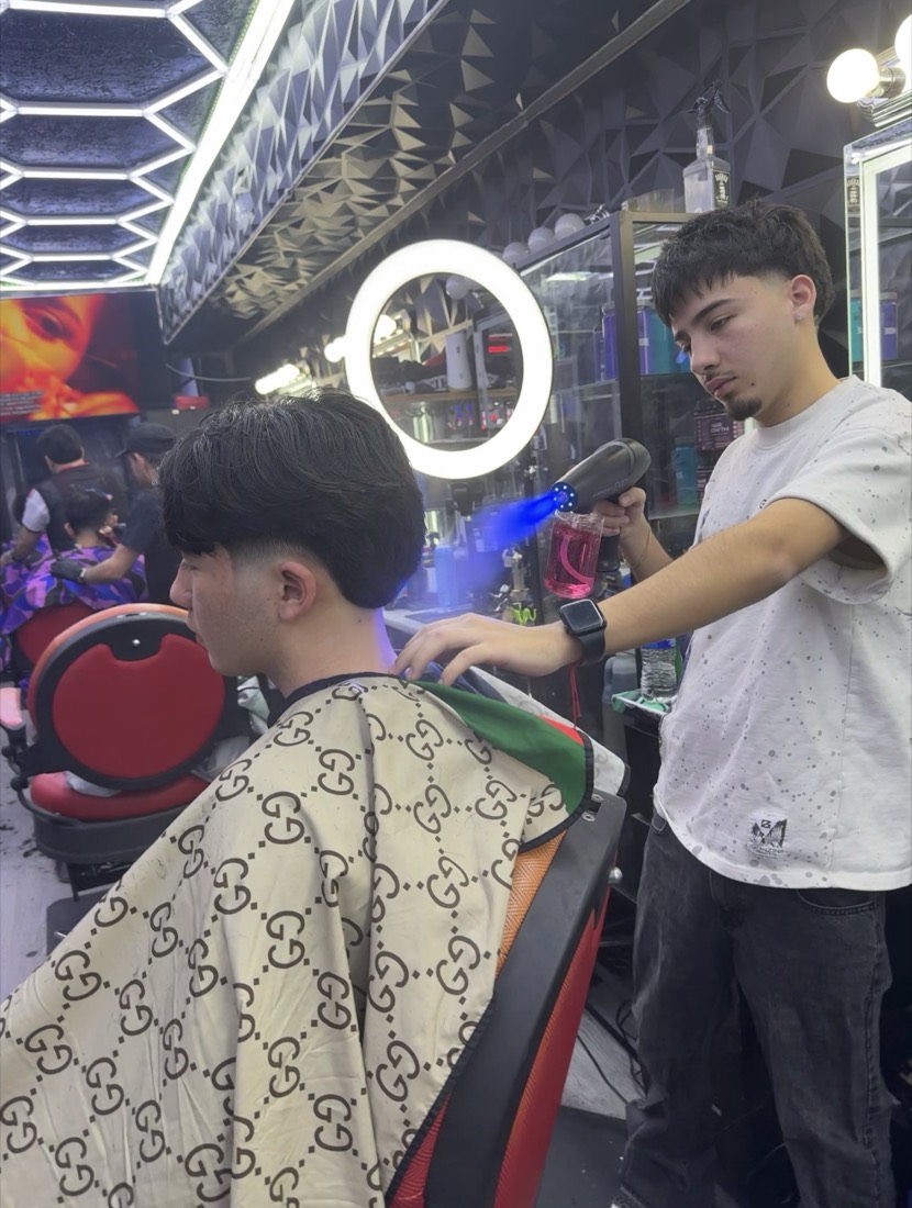 A barber drying and styling a client's hair at Morales Barbershop MB.