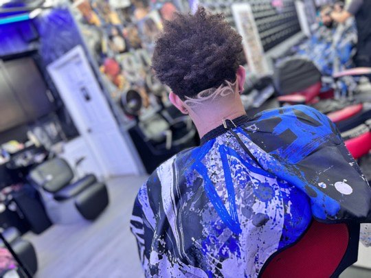 Freestyle design shaved by hand on the nape, with curls on top.