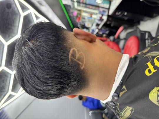 Letter B shaved by hand on the nape over a taper.