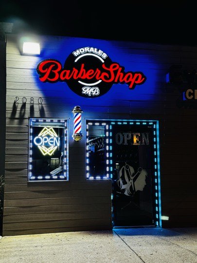 Neon sign of Morales Barbershop MB lit up at night in Hyattsville.