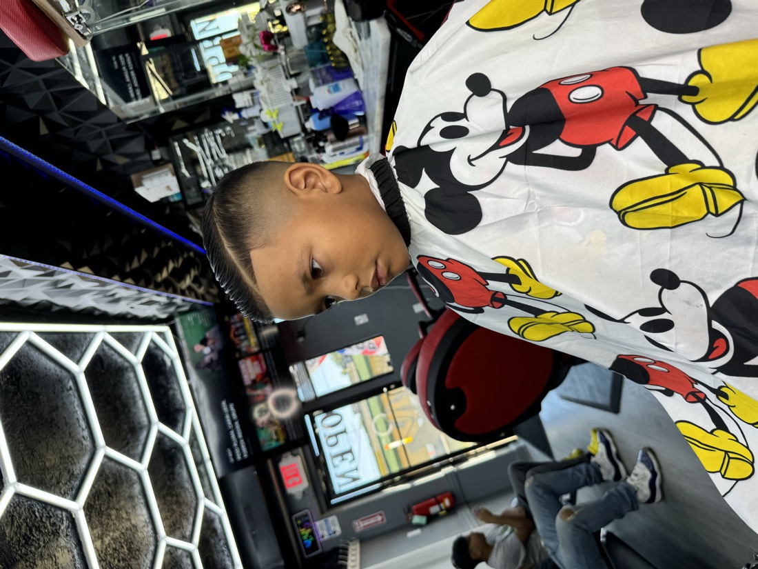 Kid with a high skin fade and a sharp line up, side view.