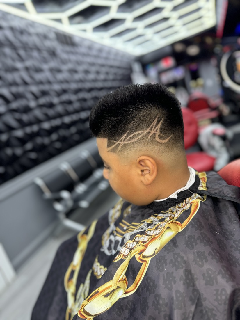 Skin fade alto con las iniciales del cliente rapadas a mano.