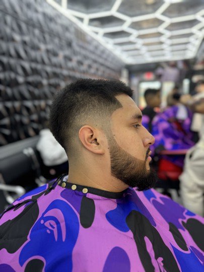 Skin fade with a trimmed and lined up beard, side view.
