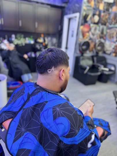 Skin fade con barba recortada y línea rapada en el lateral.